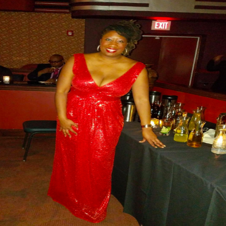 A reviewer wearing the plunging neckline, sleeveless, full-length gown in red