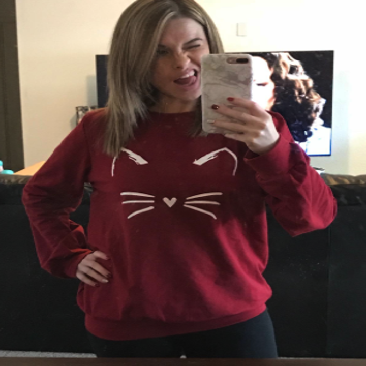 Reviewer wearing the sweatshirt in red with ears and whiskers drawn in white