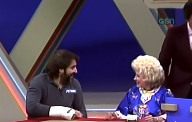 Smiling guy with a beard and his hand in a cast smiling at a woman, both of them seated