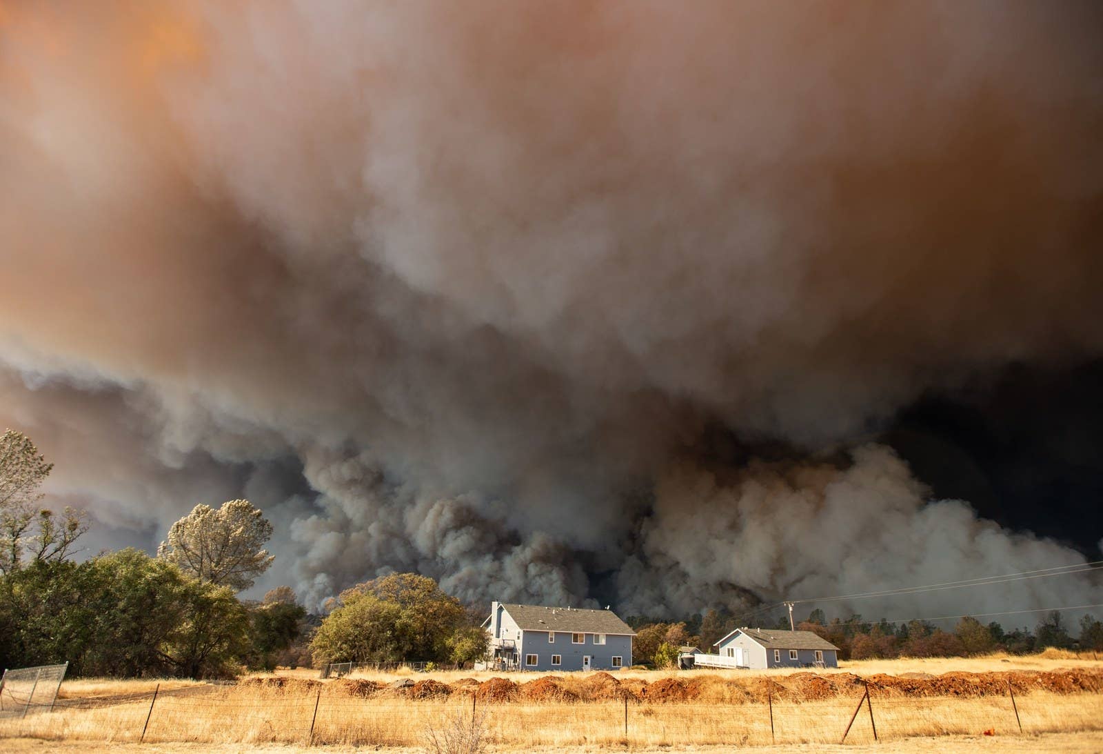 A home is overshadowed by towering smoke plumes as the Camp fire burns through Paradise on Nov. 8.