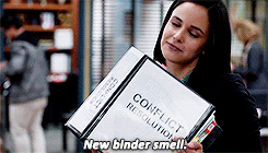 Amy from &quot;Brooklyn Nine-Nine holding a giant binder, breathing in, and saying &quot;New binder smell