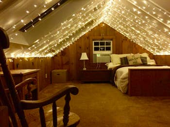 reviewer pic of lighted curtains on an A-frame ceiling in an attic bedroom