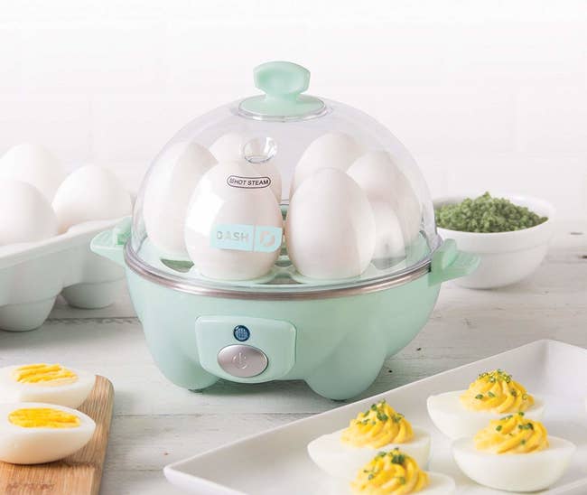 The egg cooker surrounded by eggs