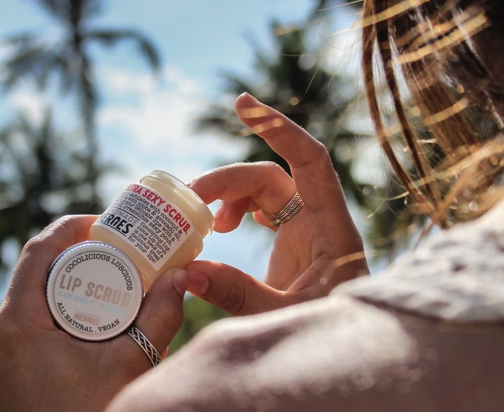 Hand dipping into container of coconut lip scrub 