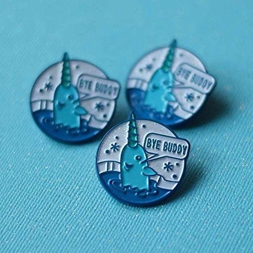 Round enamel pins with a narwhal saying &quot;bye buddy&quot; on them