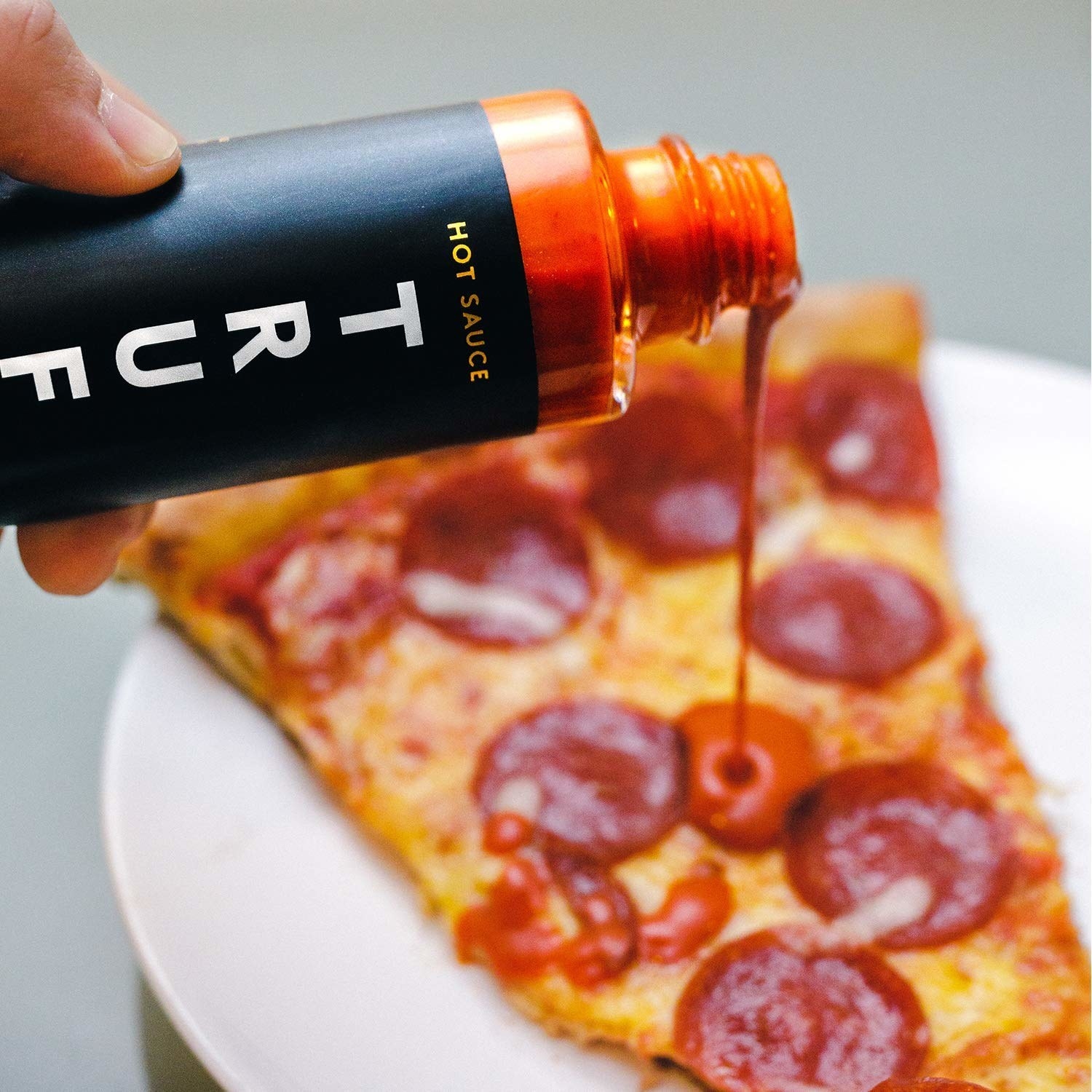 truffle hot sauce being poured on pizza