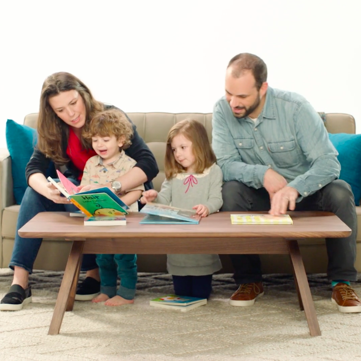 Models reading children's books to kids in a living room