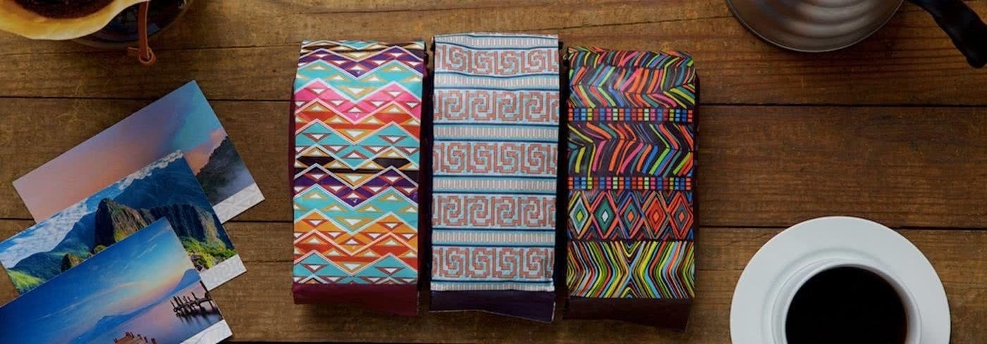 Three bags of coffee with bright and colorful patterns on each bag