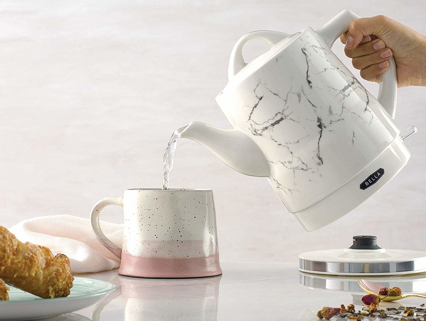 person pouring water from the marble print tea kettle into a coffee mug