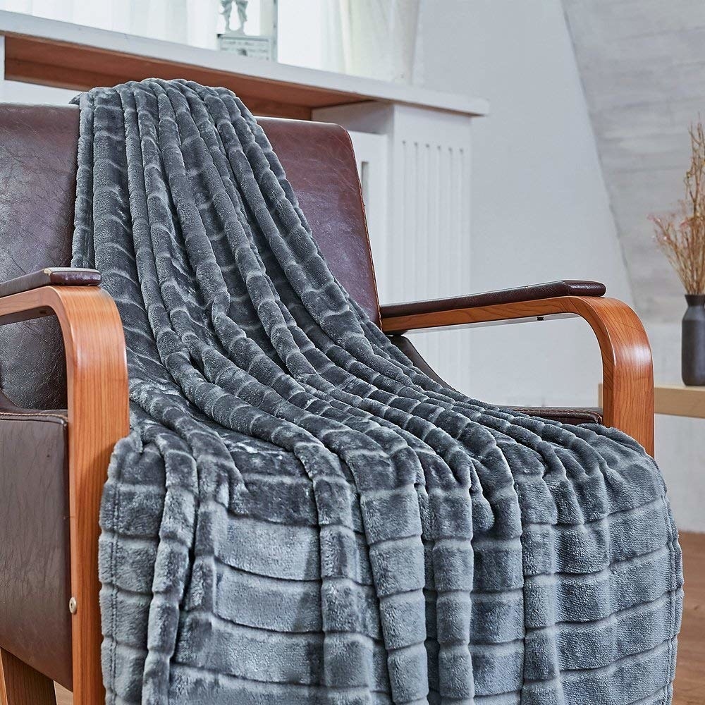 The blanket draped across a chair; it has slight stripes in its pattern