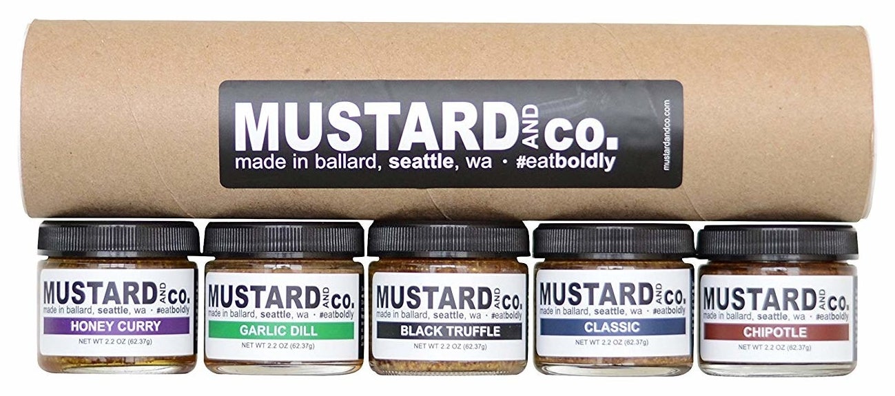A cardboard tube with five mustard sample jars 