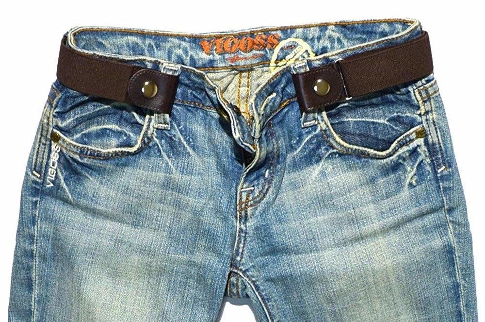 A brown snap on belt on a pair of pants 