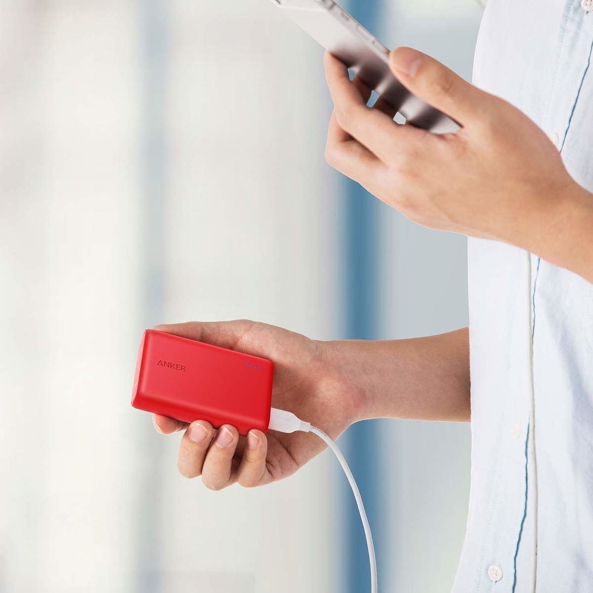 Model holds the small portable charger in their hand while holding their phone in the other hand