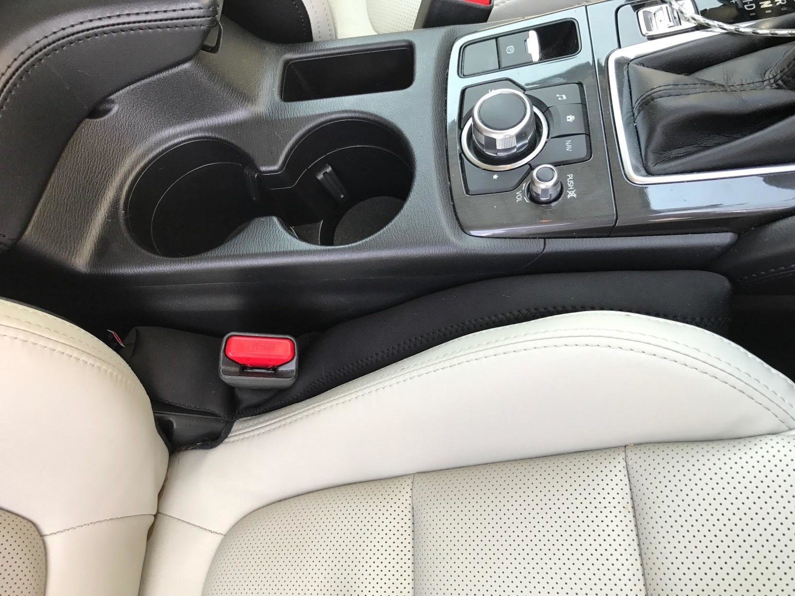 A black seat filler wedged between a seat and car console 