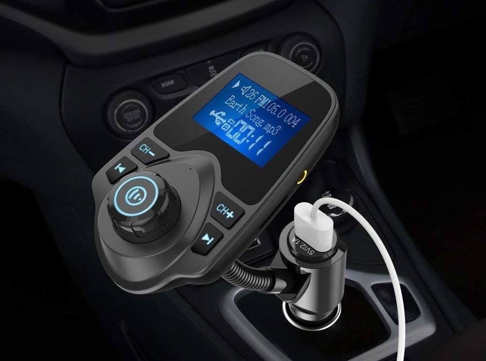 the black audio adapter plugged into a car jack with a small display screen and controls to pause and skip music 