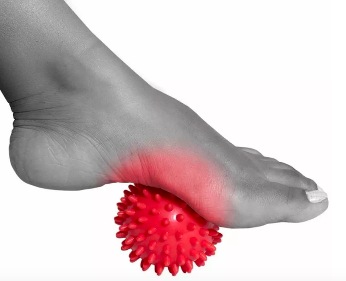 A person rolling an accupressure ball with their foot