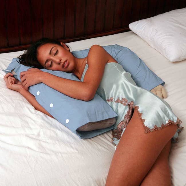 A model being spooned by the pillow shaped like a torso with an arm