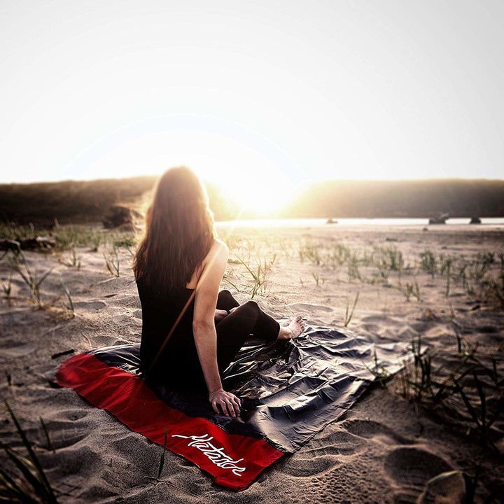 person sitting on the blanket on a beach watching the sunset