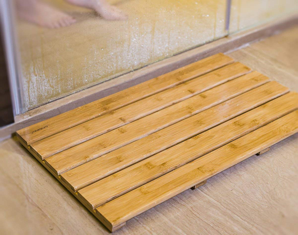 Promising review: "I bought this bathmat because we're now sharing the bathroom with my cat, and she tracks litter on the floor. I figured this would be cleaner and easier to maintain than a cloth bathmat and it 100% is. I sweep the bathroom out every day, and all I have to do is tilt this mat up, sweep underneath it, and I'm done. To clean it, I just wipe it down with a damp sponge with a little bit of bathroom cleaner sprayed on it. If you wanted to do a deep clean you could easily rinse it off in the shower or hose it down. I dry off as much as possible in the shower before I step out onto the mat, including dabbing my feet dry, and there's not a ton of water pooling. The wood is warmer to step out onto than a bare tile floor. The plastic grips definitely make it slip-free and level. The design looks great. This is a good product for the value." —Laura Edwins Get it from Amazon for $37.99.