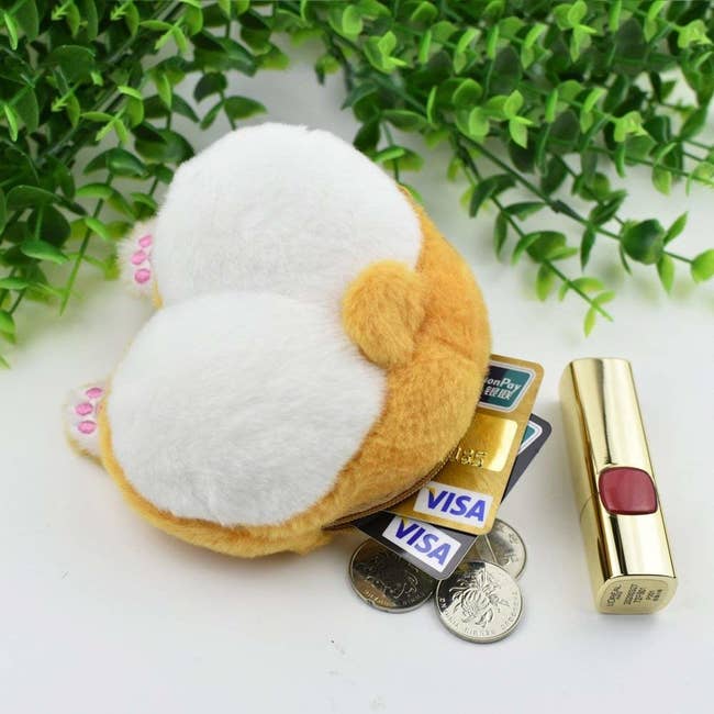 The furry coin purse with tail, little paws, and showing it fitting a lipstick, two credit cards, and coins