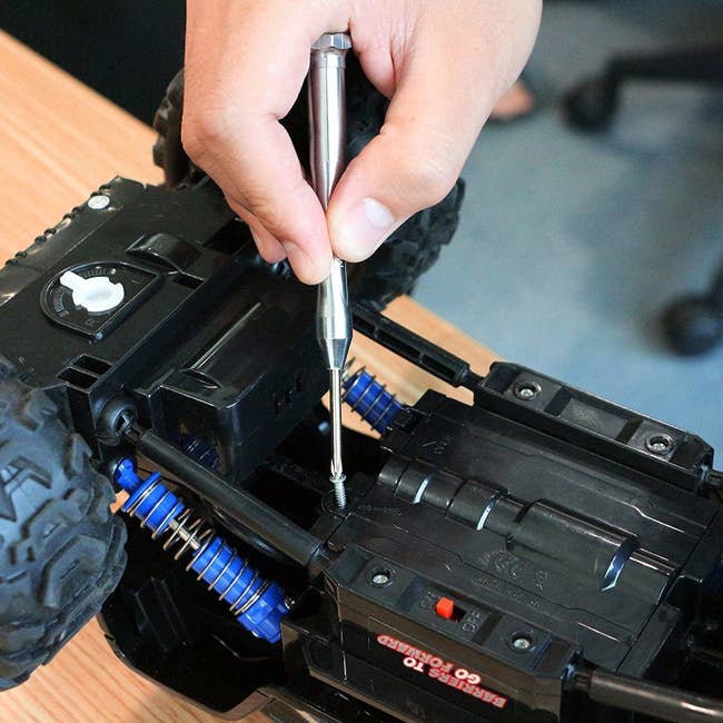 person using the screwdriver on a toy car
