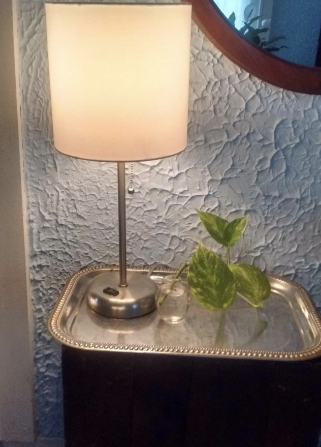 Reviewer photo of the lamp with a silver base sitting on a bedside table