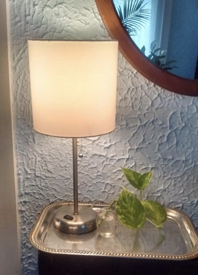 Reviewer photo of the lamp with a silver base sitting on a bedside table