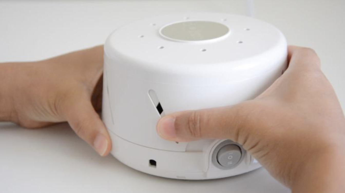 reviewer holding the round white noise machine