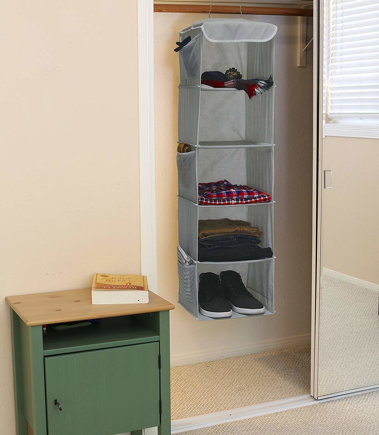 Five-tier hanging shelf with three mesh pockets on the side hanging in a closet in a bedroom