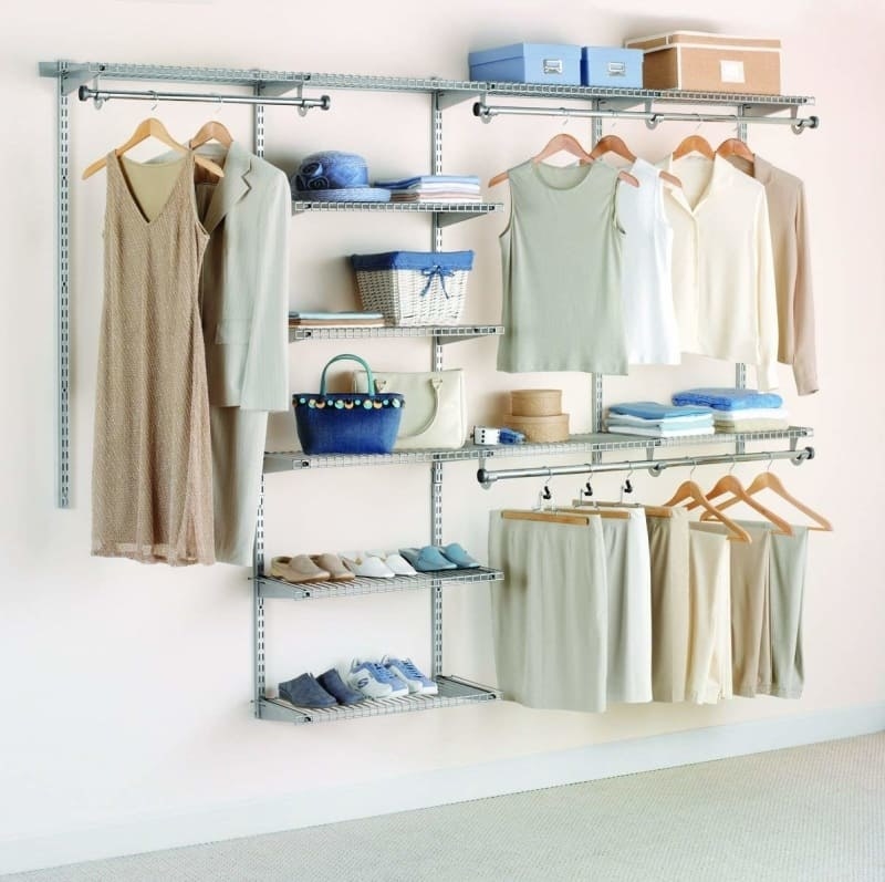 The system with three different areas to hand things and seven shelves of different lengths attached to a wall with clothes, shoes, and accessories in it