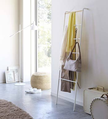 The white ladder holding blankets, a bag, a belt, and more