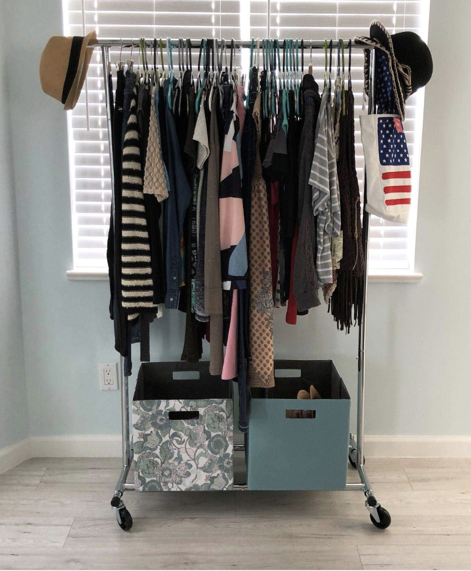 Reviewer photo of the rack  with lots of clothes hung on the rod, accessories handing from the ends and two cubes at the bottom holding shoes