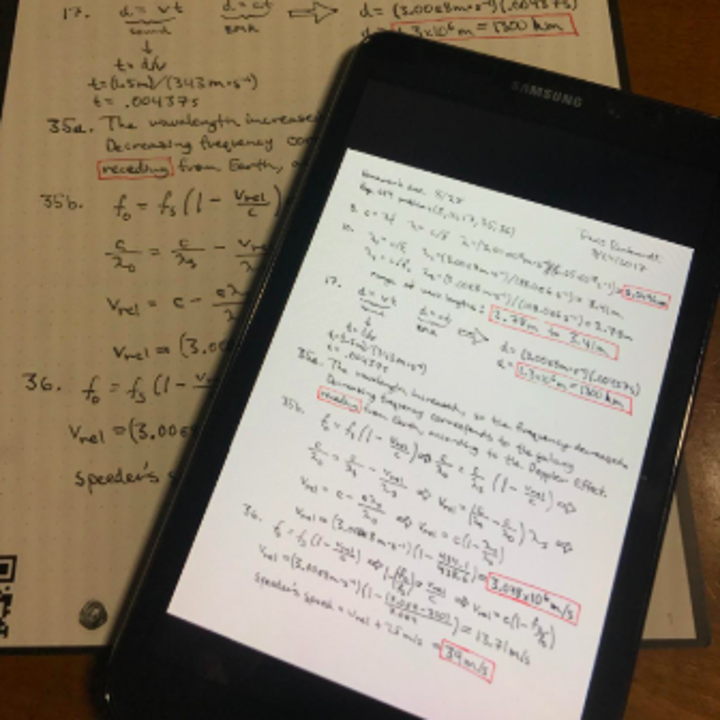 A reviewer's page of notes in the notebook and a smartphone with the same notes on the screen