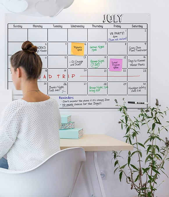 Large, clear, calendar on wall with info written with dry erase markers 