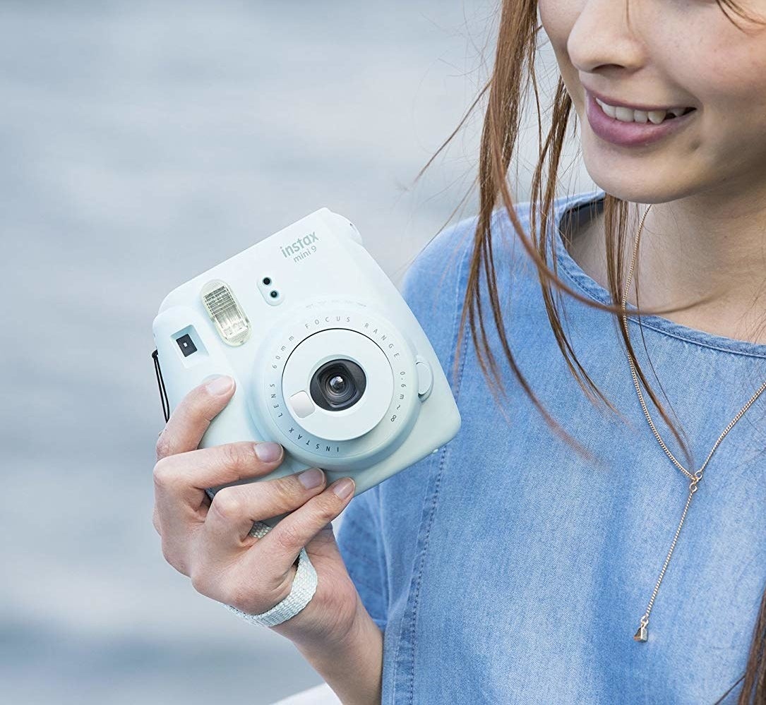 model holding light blue instax camera