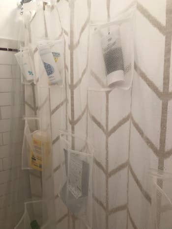 BuzzFeed editor Elizabeth's shower shown from the inside, with the clear liner holding her bath products in the several large pockets evenly spaced throughout