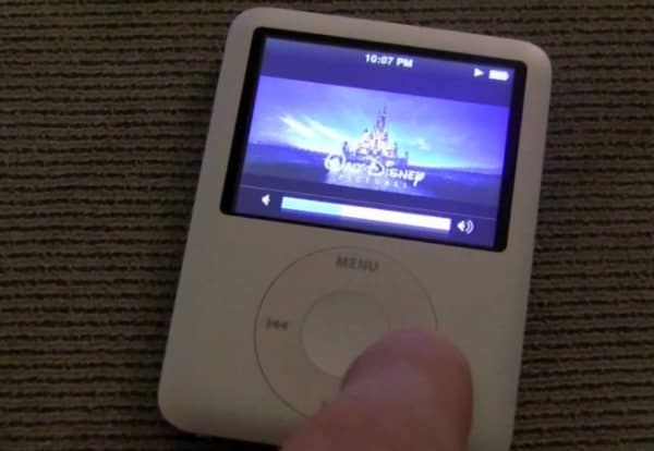 A finger pushing the forward button an iPod Mini that is playing a Disney Movie