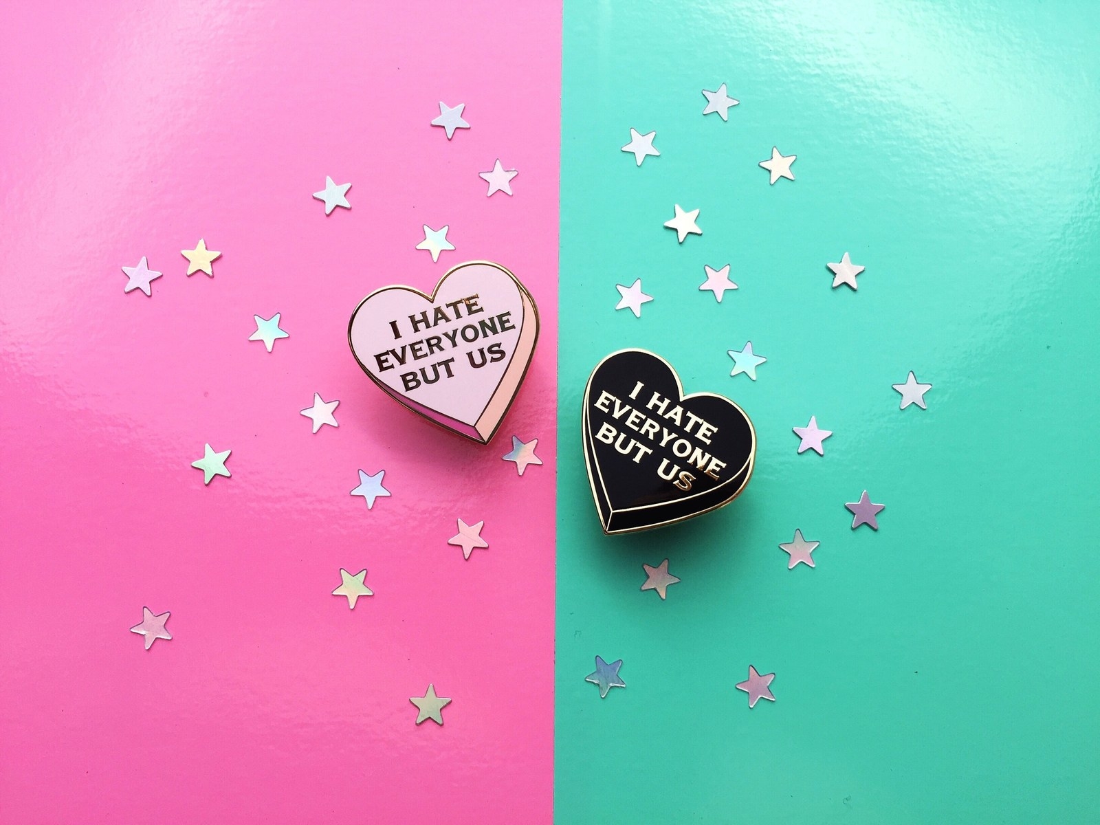 two heart shaped pins (one pink, one black) that say I hate everyone but us
