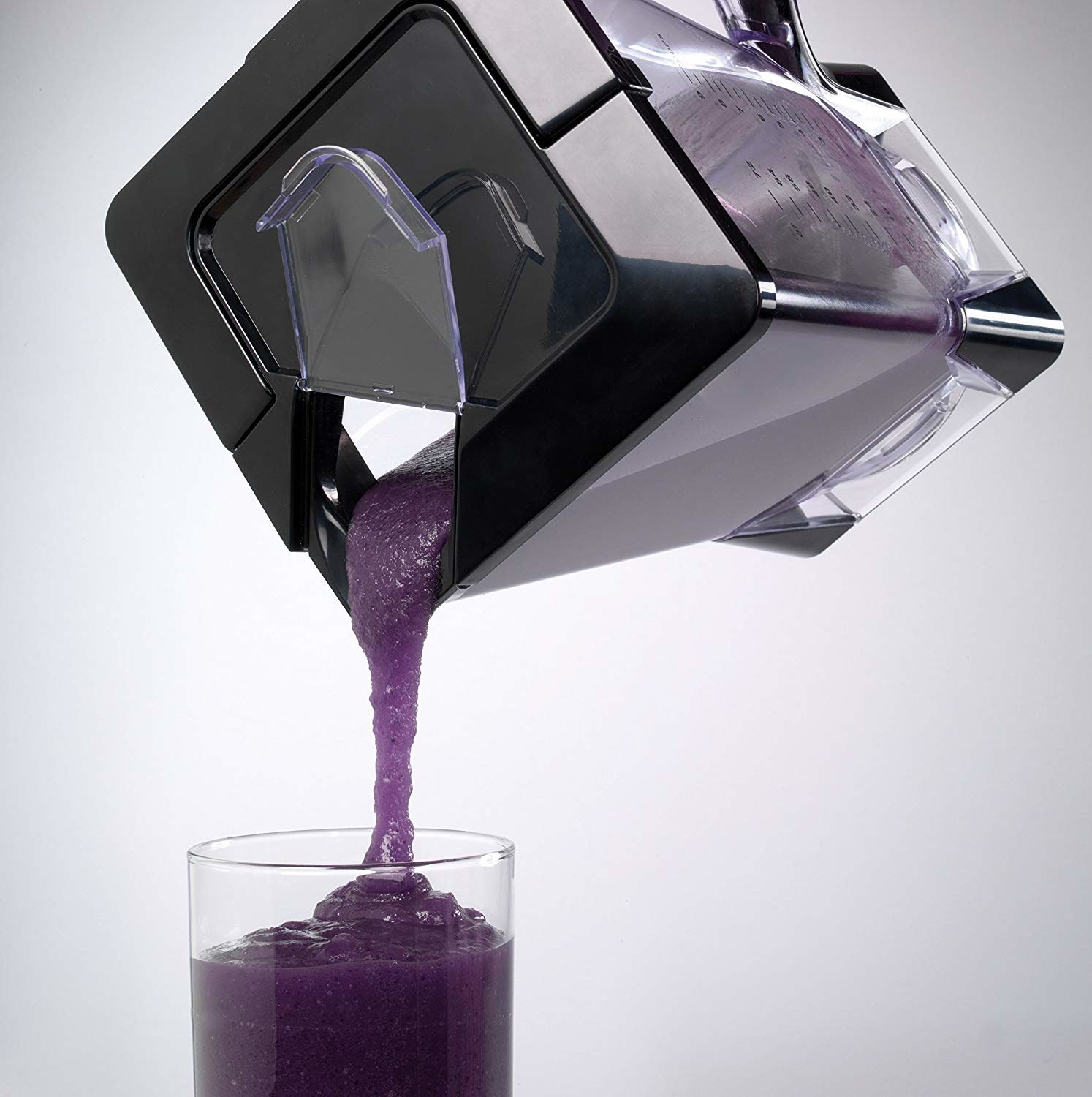 Blender with smoothie mix pouring into glass cup 