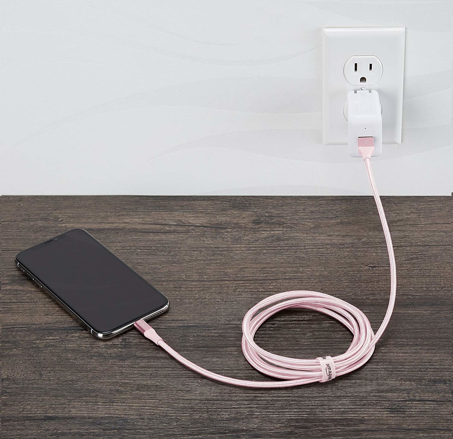 a phone attached to a long woven charging cord in pink