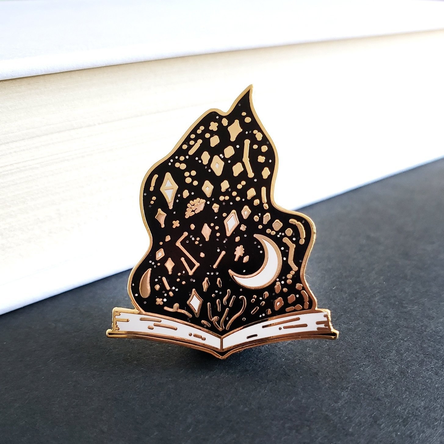a small book opened with a black flame filled with astrological symbols inside of it