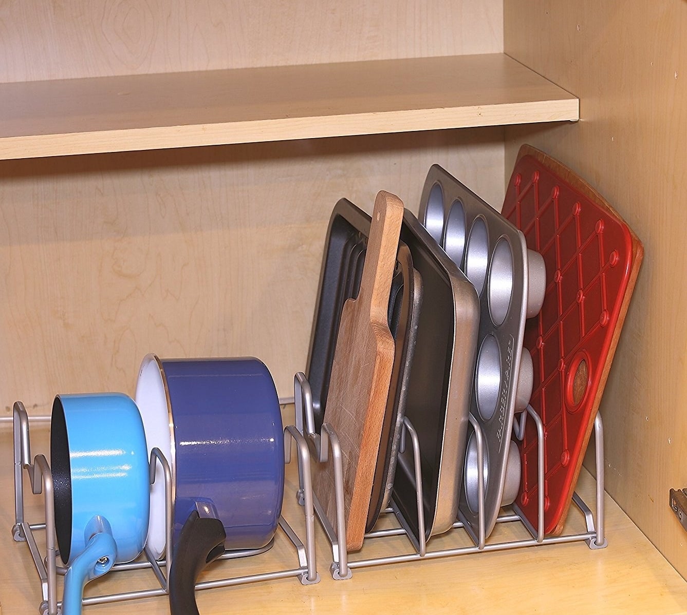 the bakeware rack in a cabinet holding two pots and some baking trays