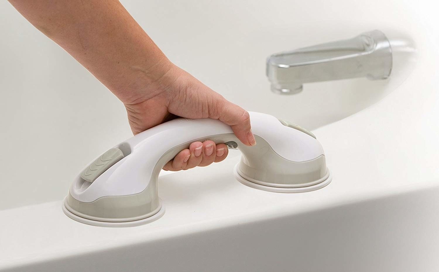 A hand gripping handle on bathtub ledge