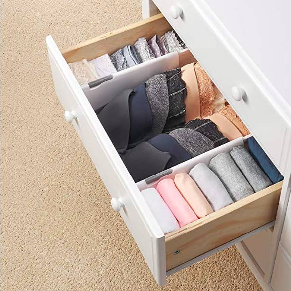 a drawer pulled out with three sections created by the separators. The sections include panties, bras, and tees.