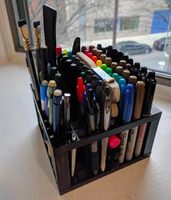 A review image where the cube is filled with markers, pens, pencils, and a few paint brushes 