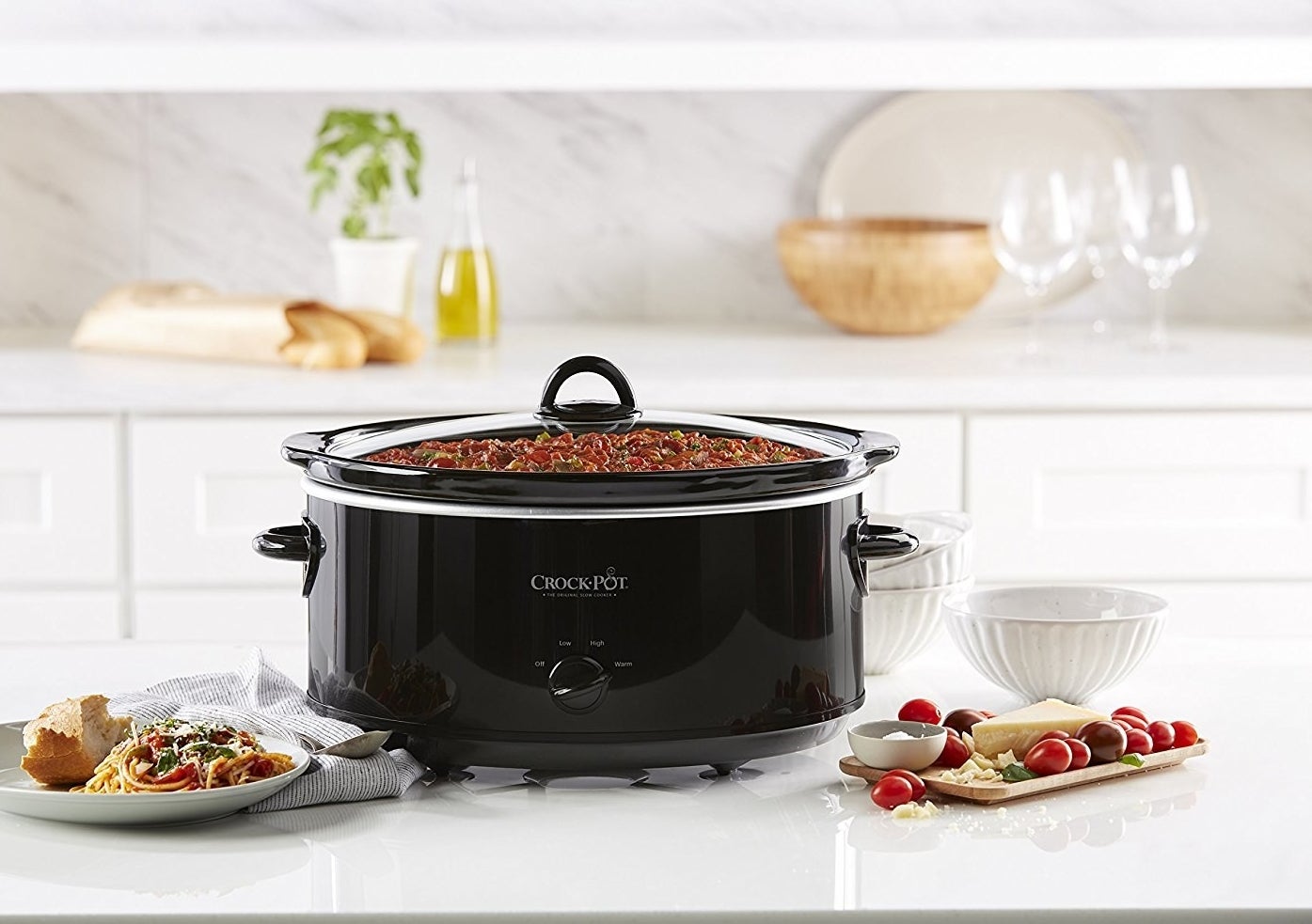 The crock pot filled with and surrounded by food