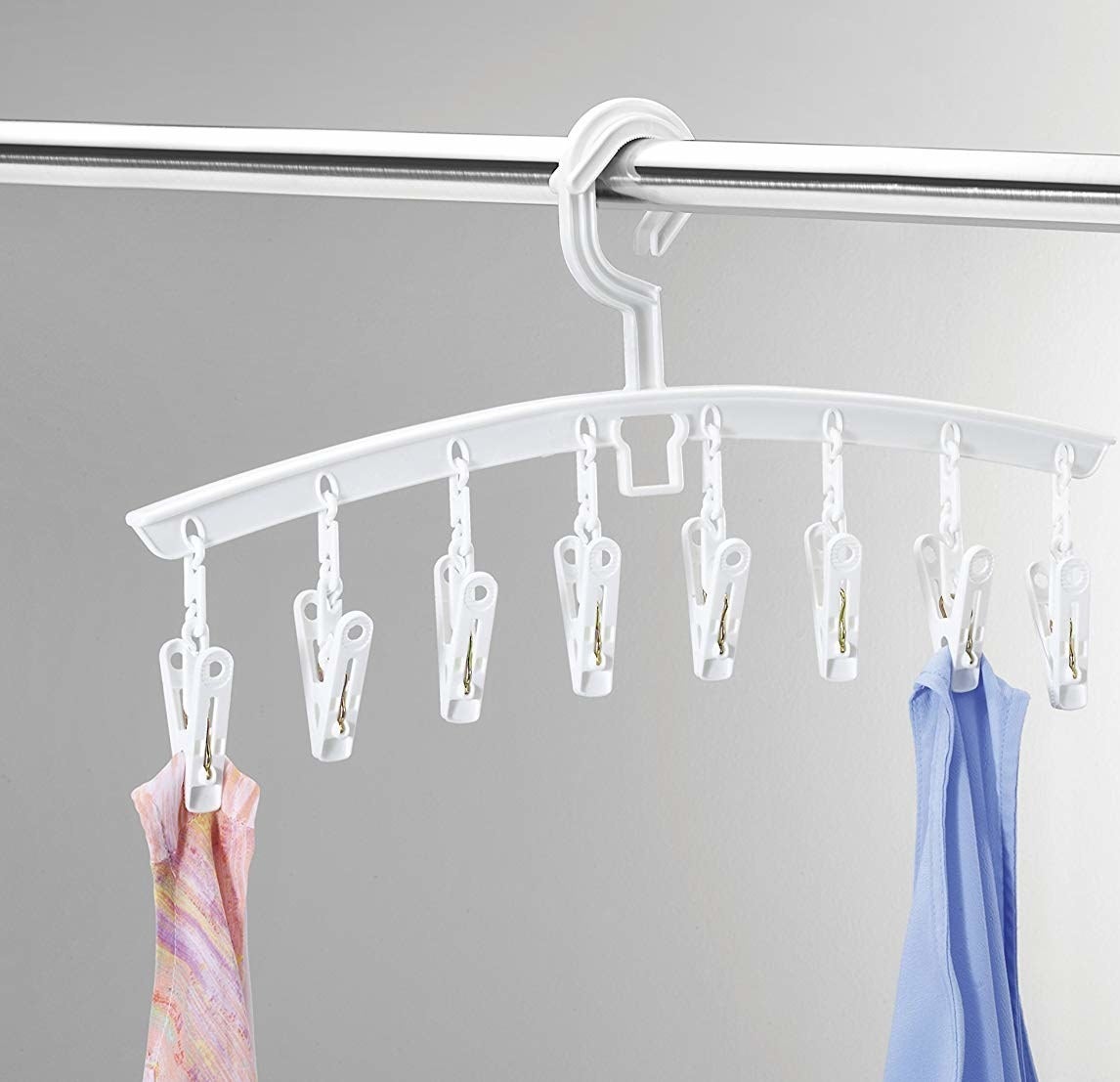 A wide hanger with eight little clips hanging from it There are two scarves hanging from the clips