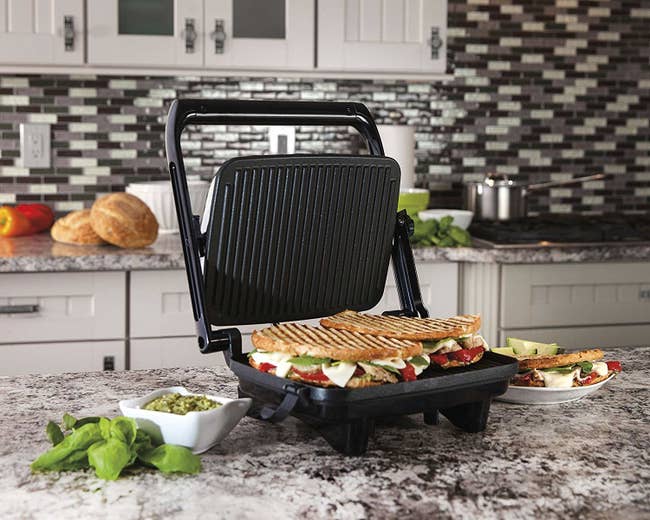 The panini press open to reveal a sandwich