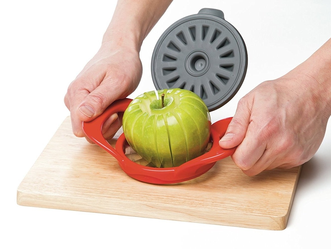 A person using the tool to cut an apple