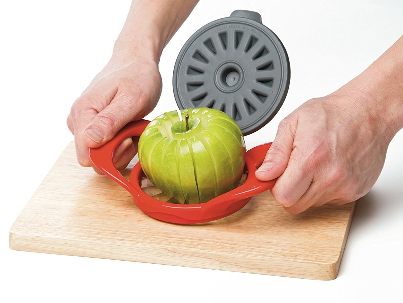 Someone using the red slicer on a green apple